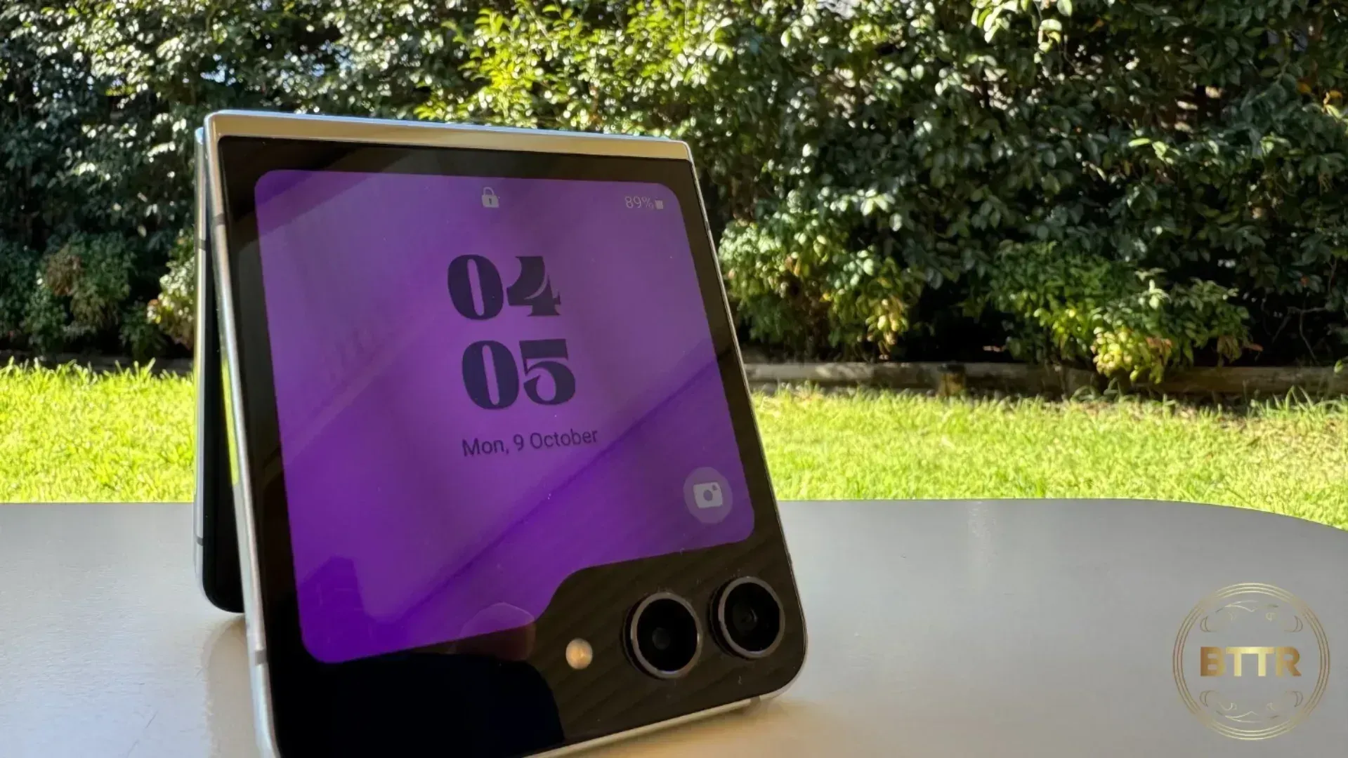 The Galaxy Z Flip 5 on a table in front of a garden