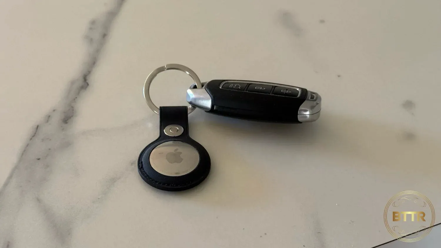 An AirTag in a keyring attachment on a benchtop
