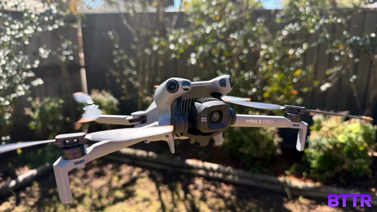The DJI Mini 5 Pro hovering in front of a garden