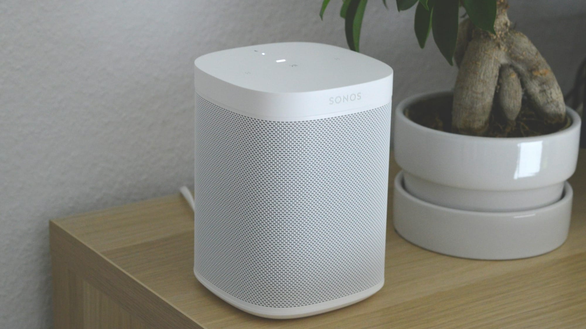 white portable Sonos speaker on brown wooden table
