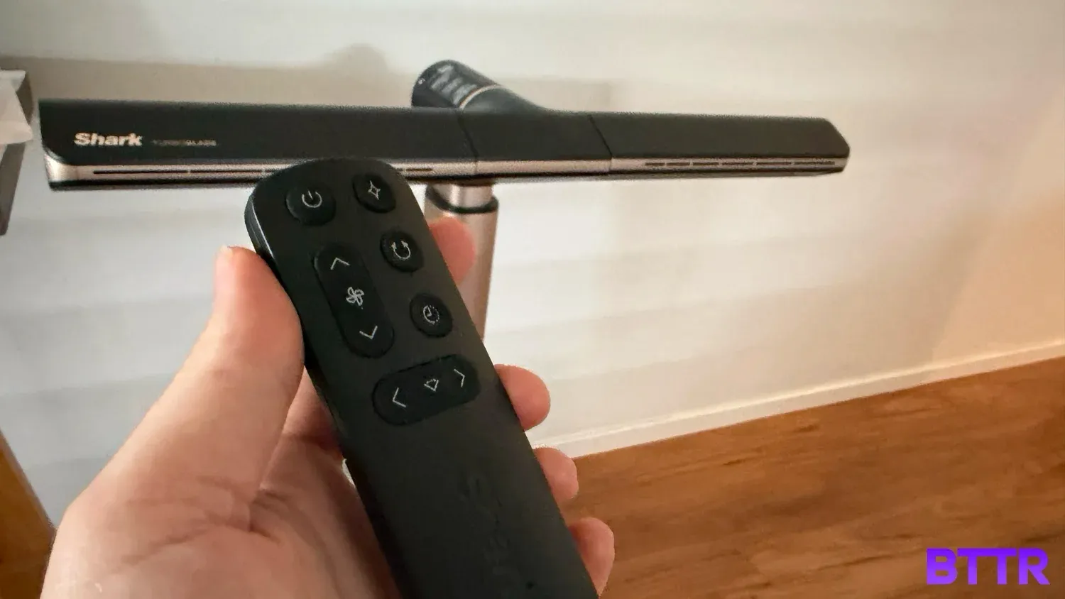 Holding the remote in front of the fan.