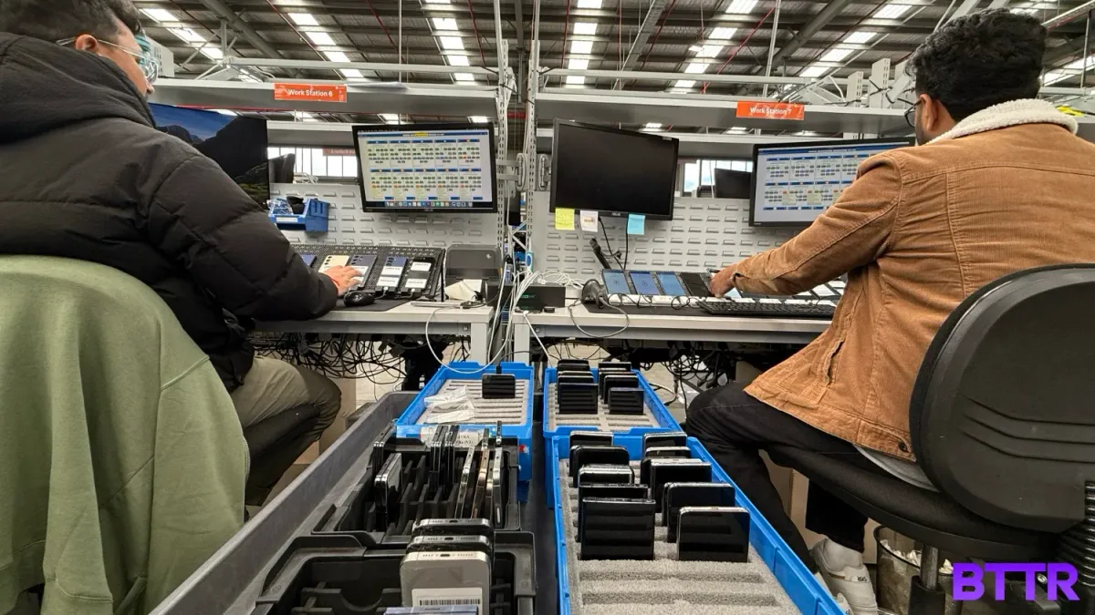 Two workers running comprehensive tests on used phones at the Assurant warehouse.