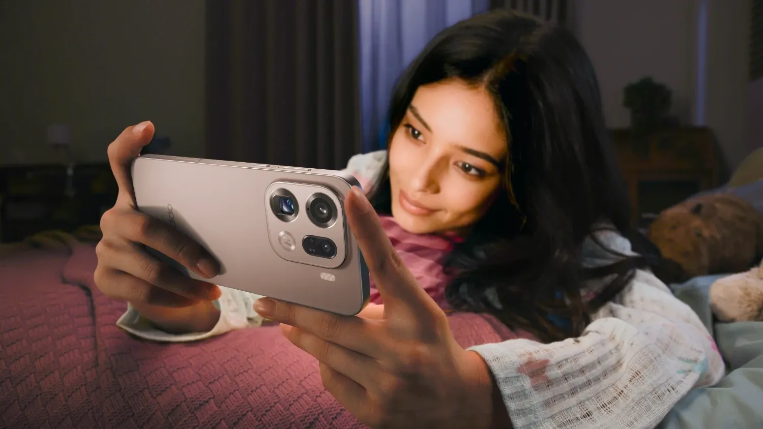 A woman on a bed holding the Find X9 Pro