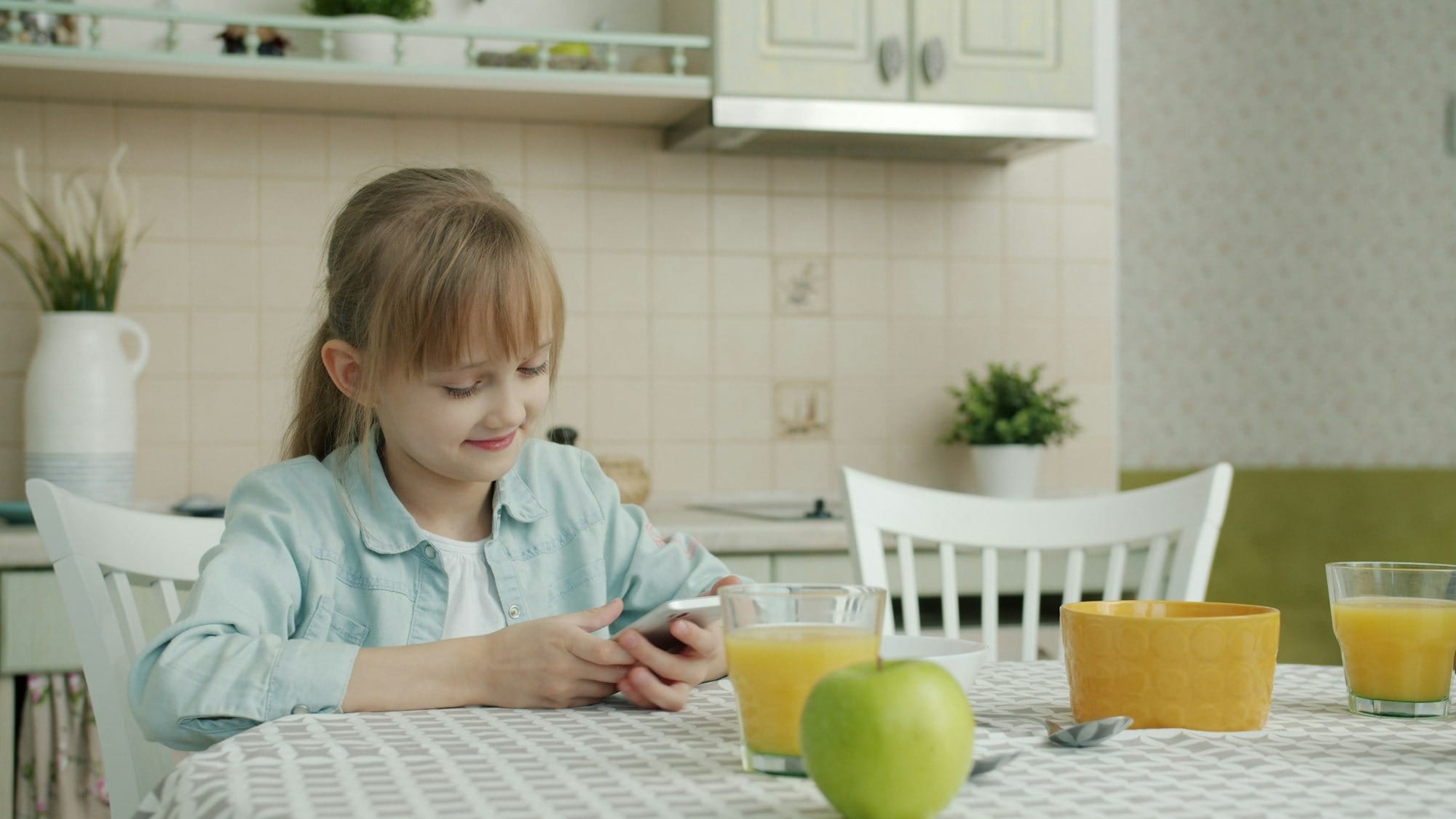 a girl on her phone at a breakfast table
