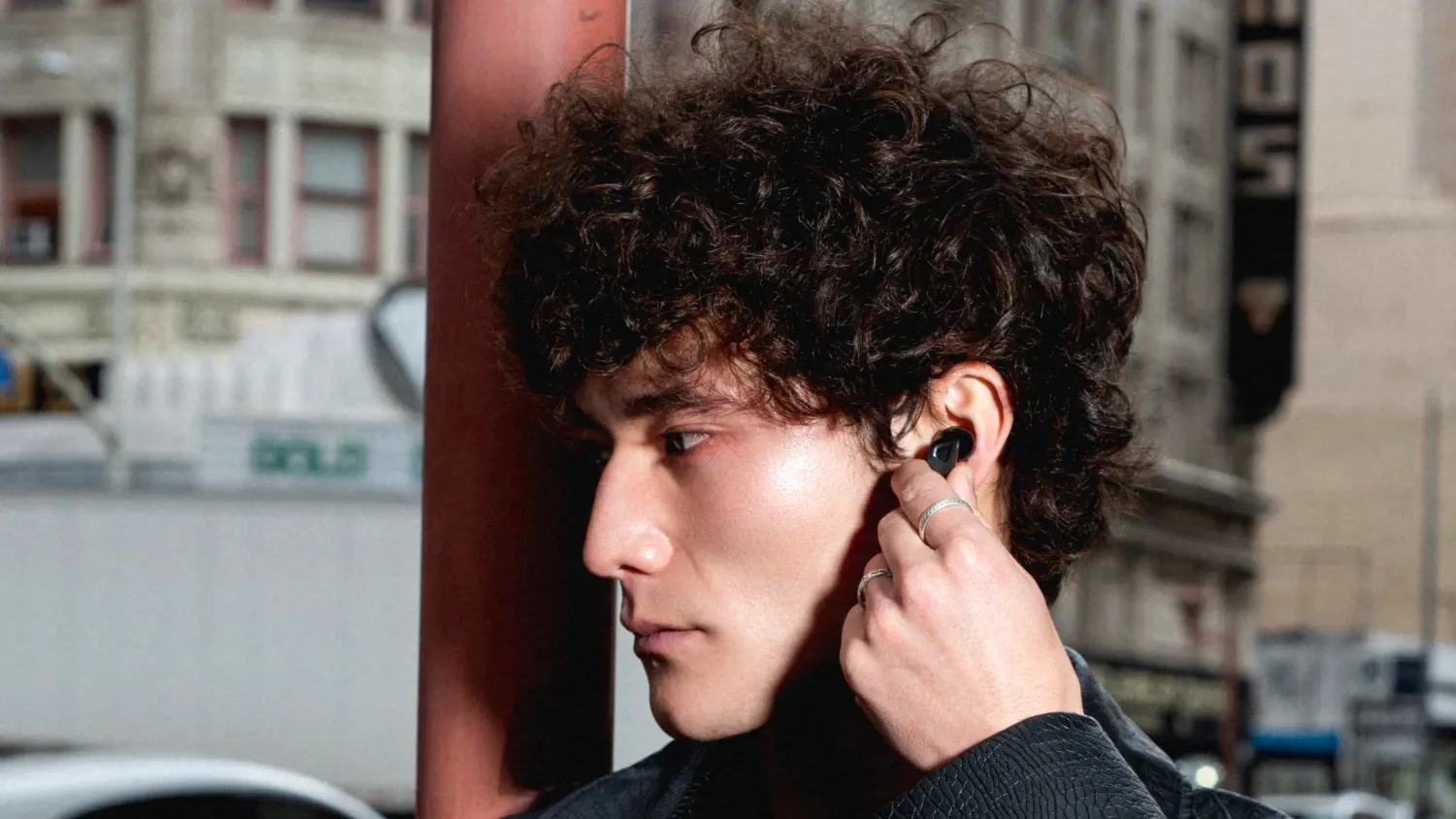 A man with curly hair with an edifier earbud in his ear