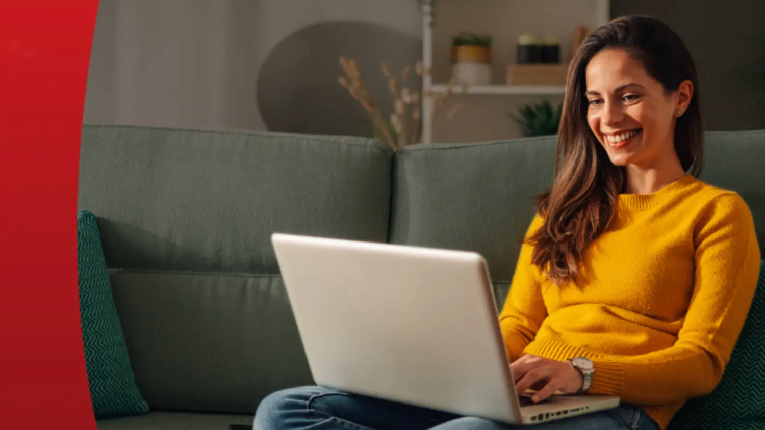 A woman smiling while using a laptop on a lounge
