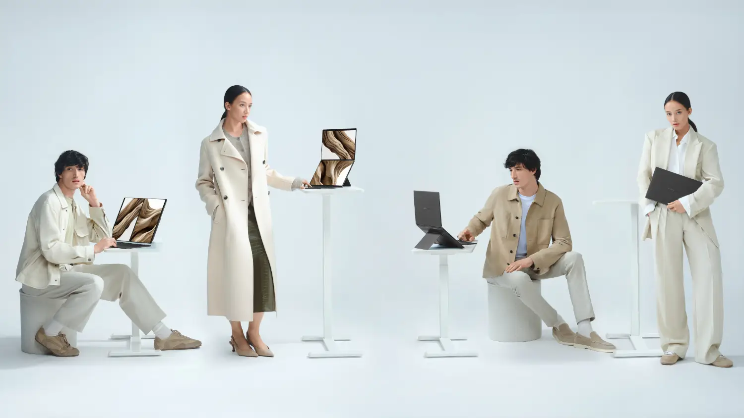 4 people dressed in white and beige using Zenbook Dos on pedestals at different heights